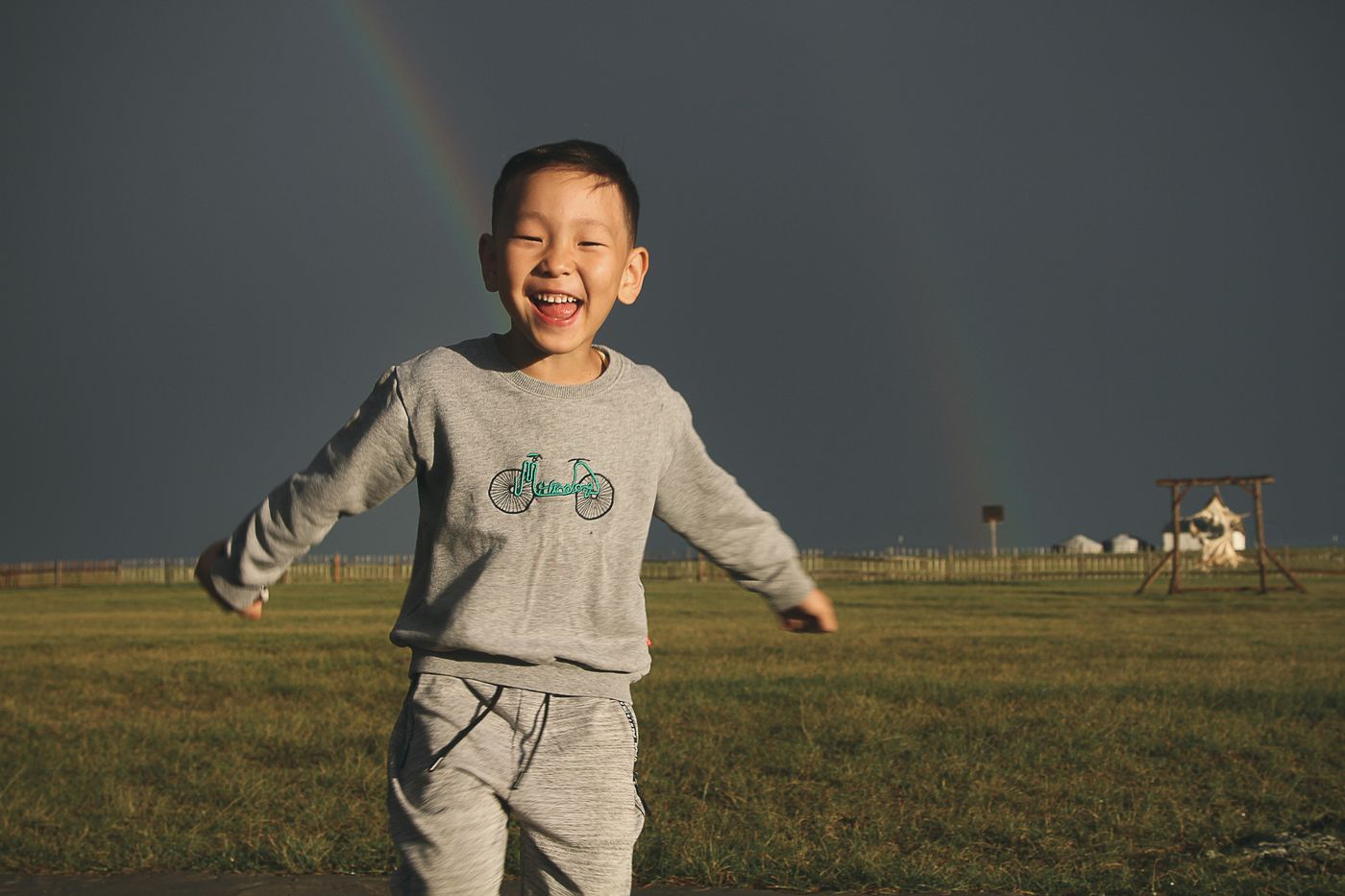 A child running joyfully beneath a rainbow